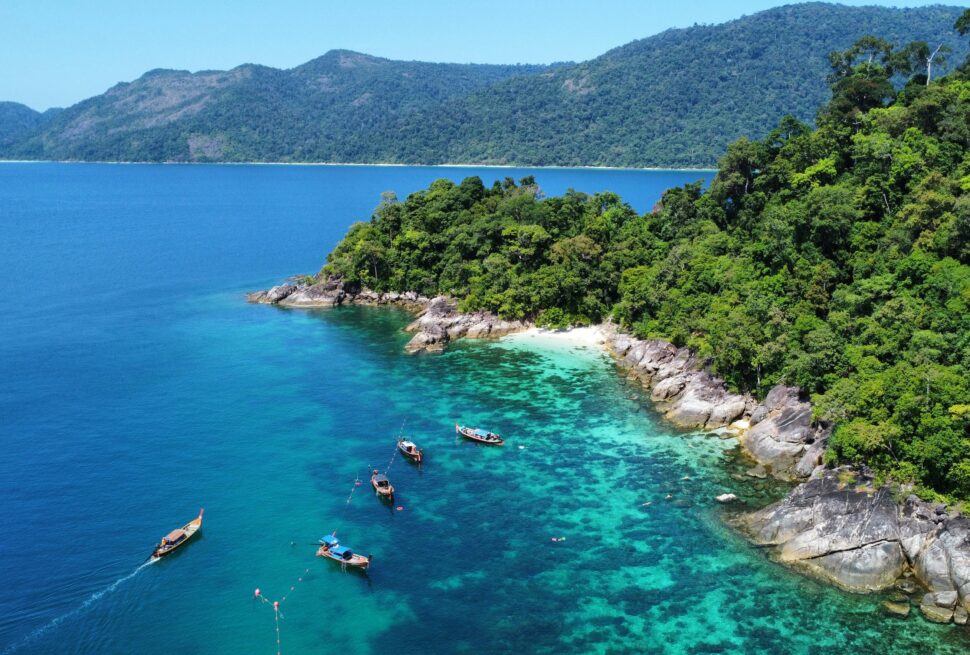 Pemandangan alam pesisir pantai tropis dan perahu tradisional di wilayah Andaman Thailand untuk panduan wisata Shelby Tour.