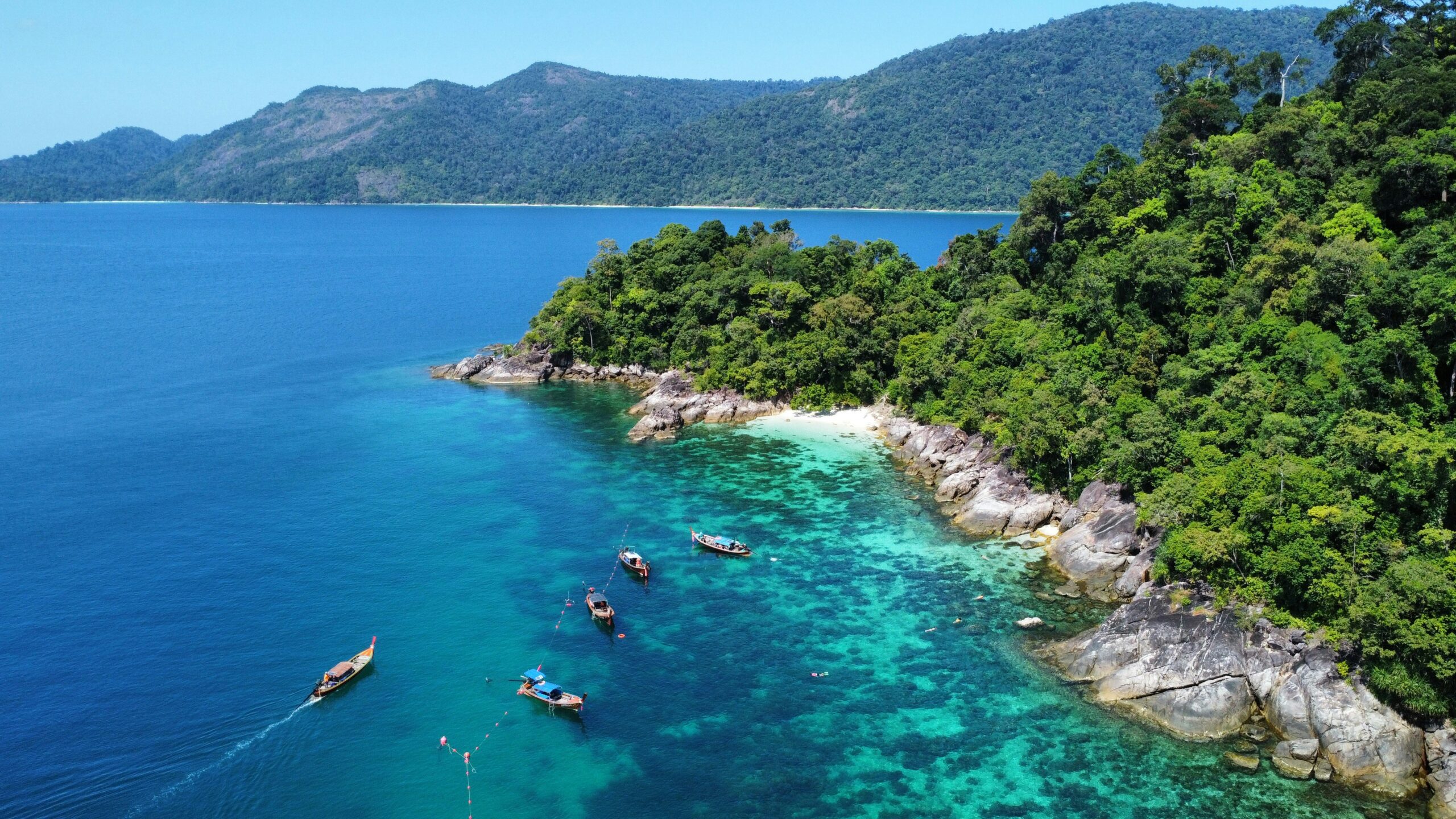Pemandangan alam pesisir pantai tropis dan perahu tradisional di wilayah Andaman Thailand untuk panduan wisata Shelby Tour.